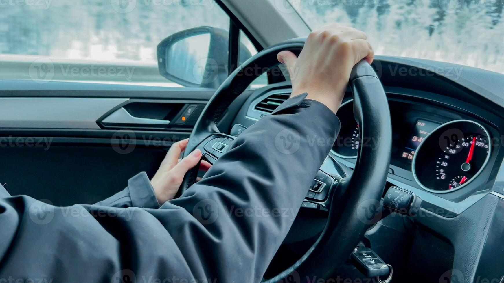 Person driving a car with focus on hands and steering wheel, suggesting safe driving during winter conditions or travel themed content photo
