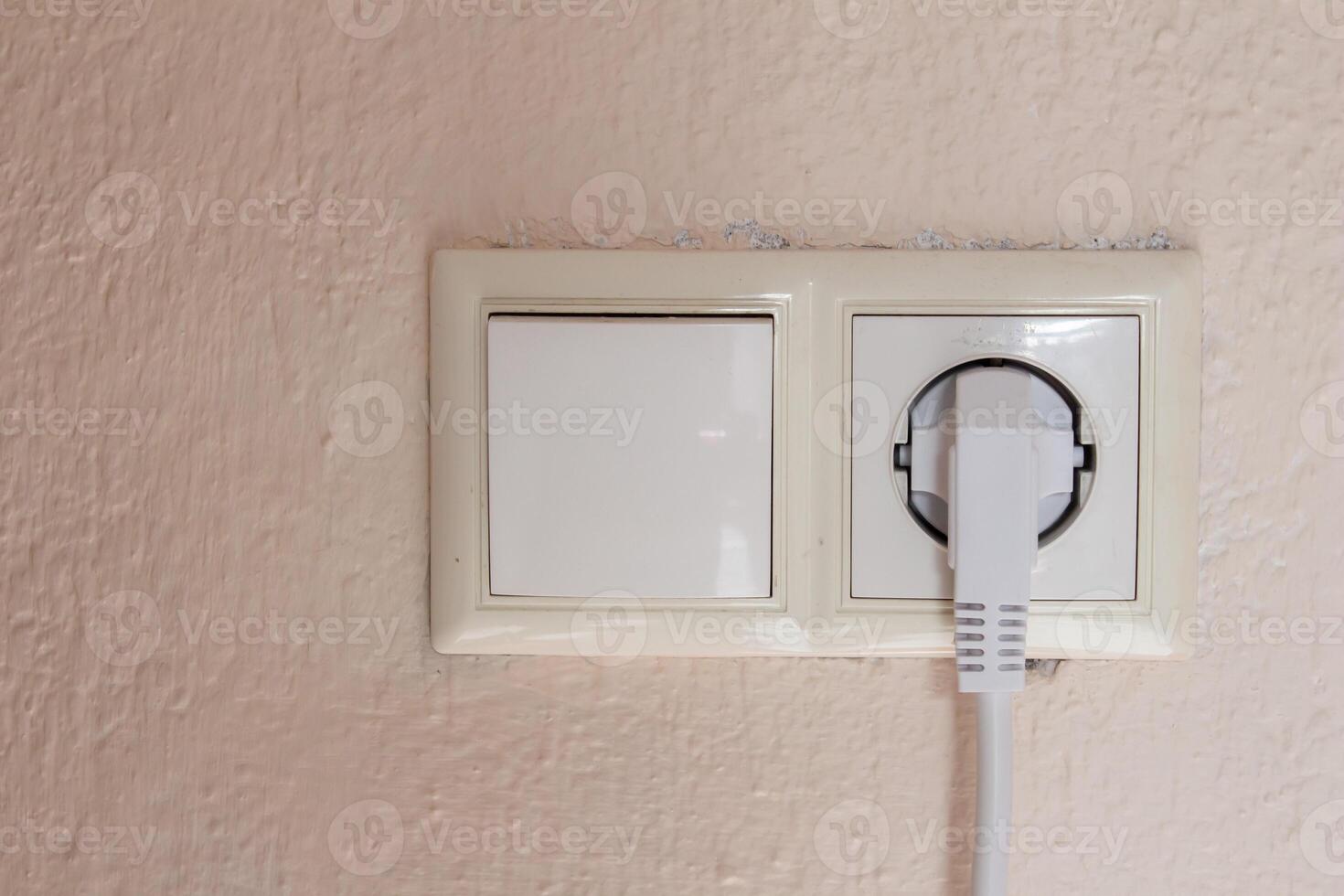 A plug in socket, concrete wall front view photo