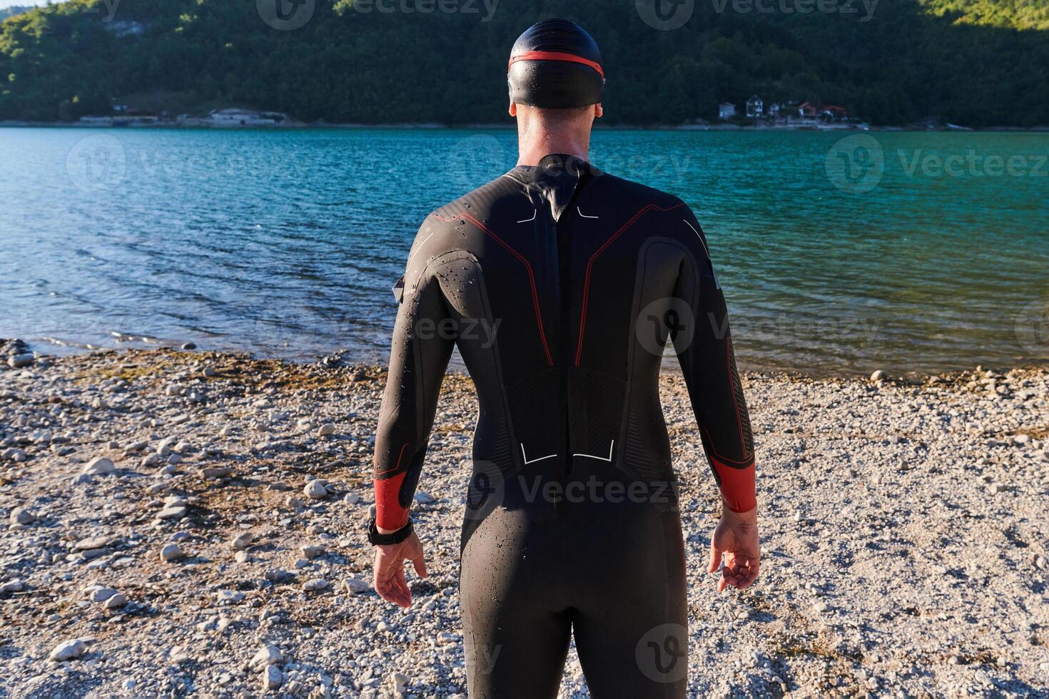 Authentic triathlon athlete getting ready for swimming training on lake photo