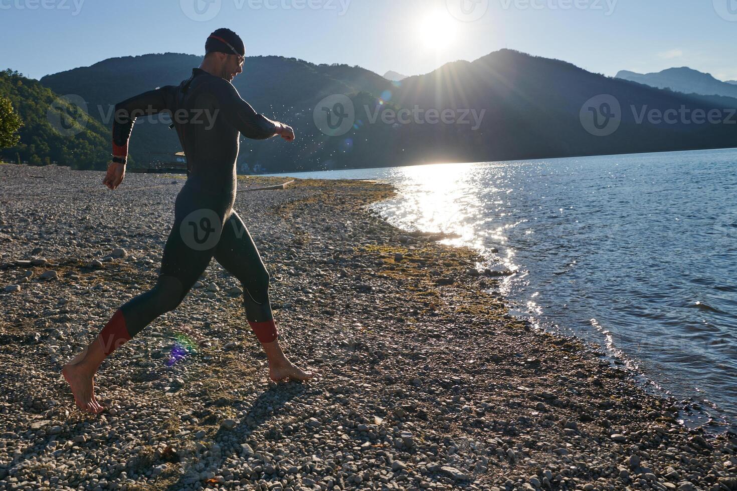 Triathlon athlete starting swimming training on lake photo