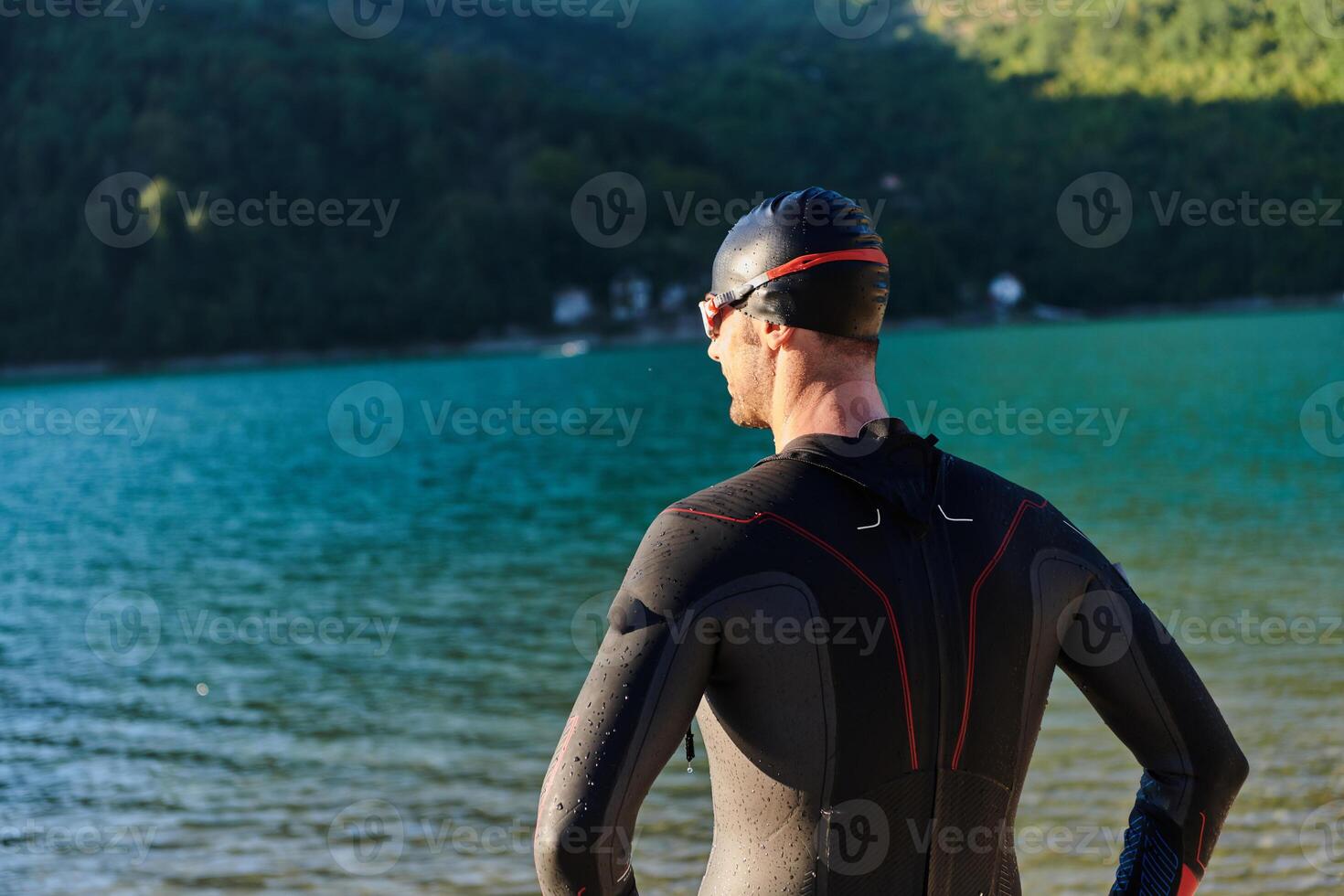 Authentic triathlon athlete getting ready for swimming training on lake photo