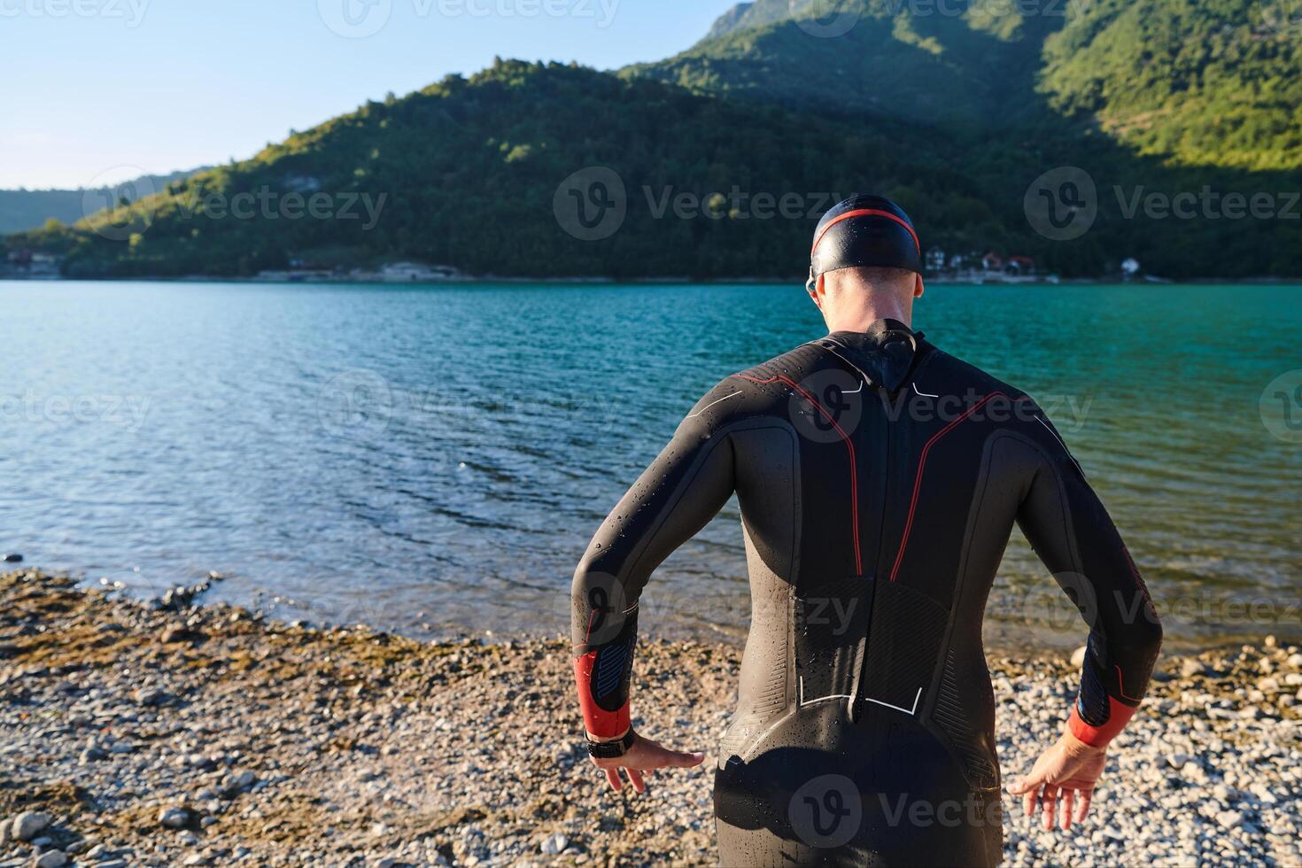 Authentic triathlon athlete getting ready for swimming training on lake photo