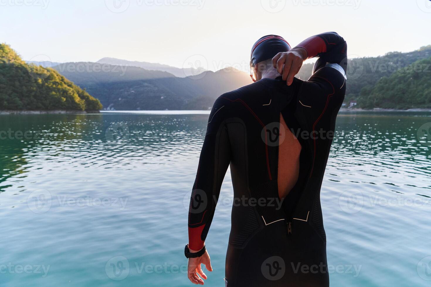 Authentic triathlon athlete getting ready for swimming training on lake photo