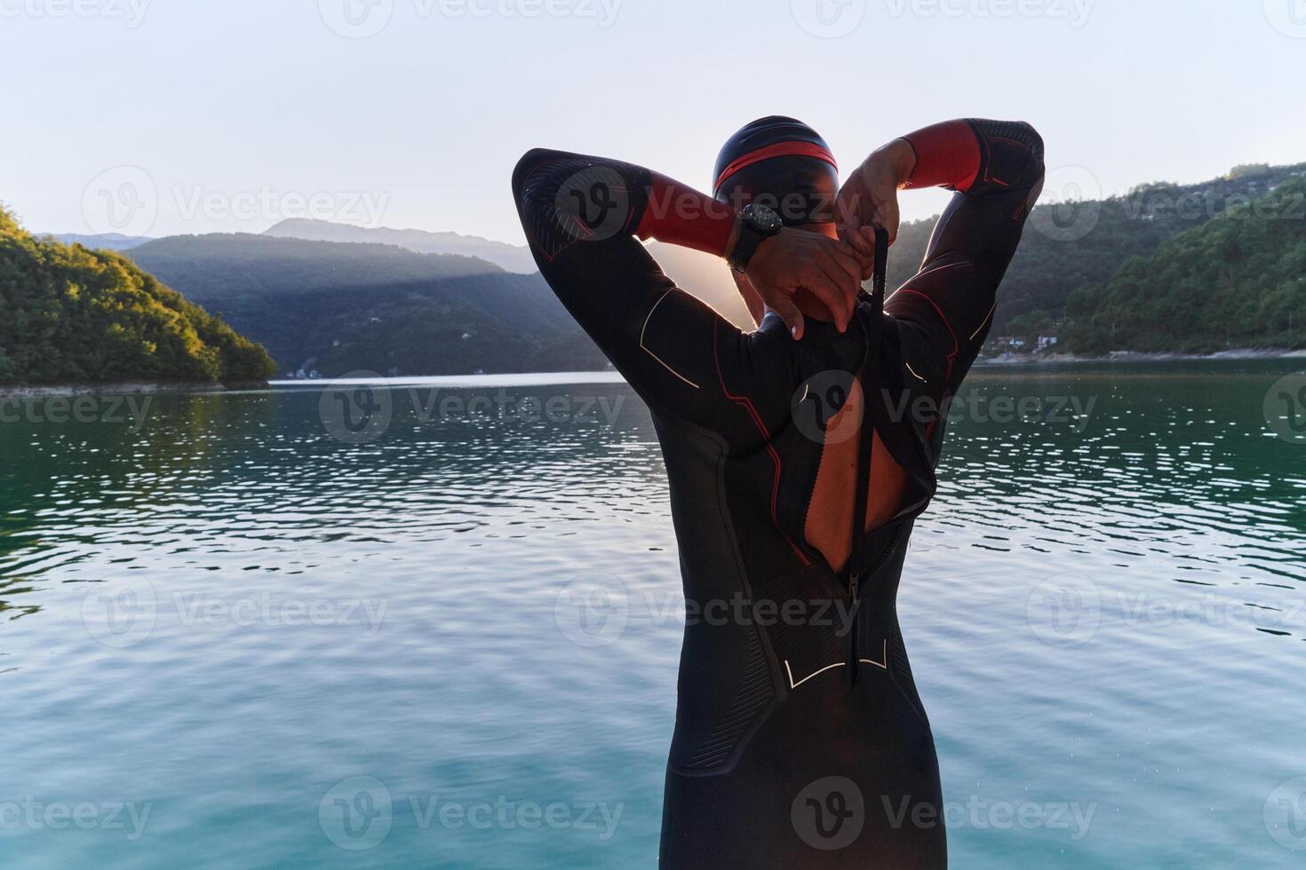 Authentic triathlon athlete getting ready for swimming training on lake photo