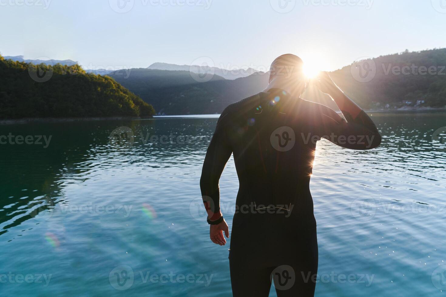 Authentic triathlon athlete getting ready for swimming training on lake photo