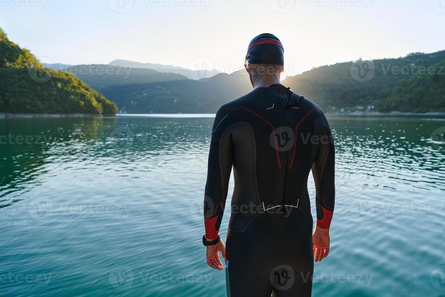 Authentic triathlon athlete getting ready for swimming training on lake photo