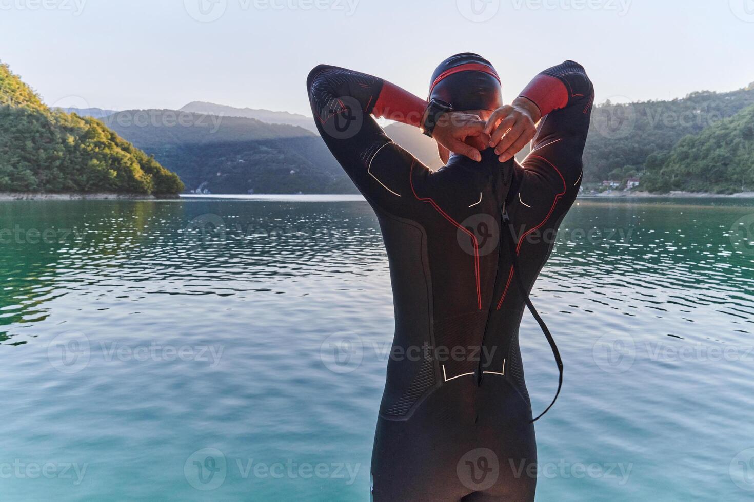 Authentic triathlon athlete getting ready for swimming training on lake photo