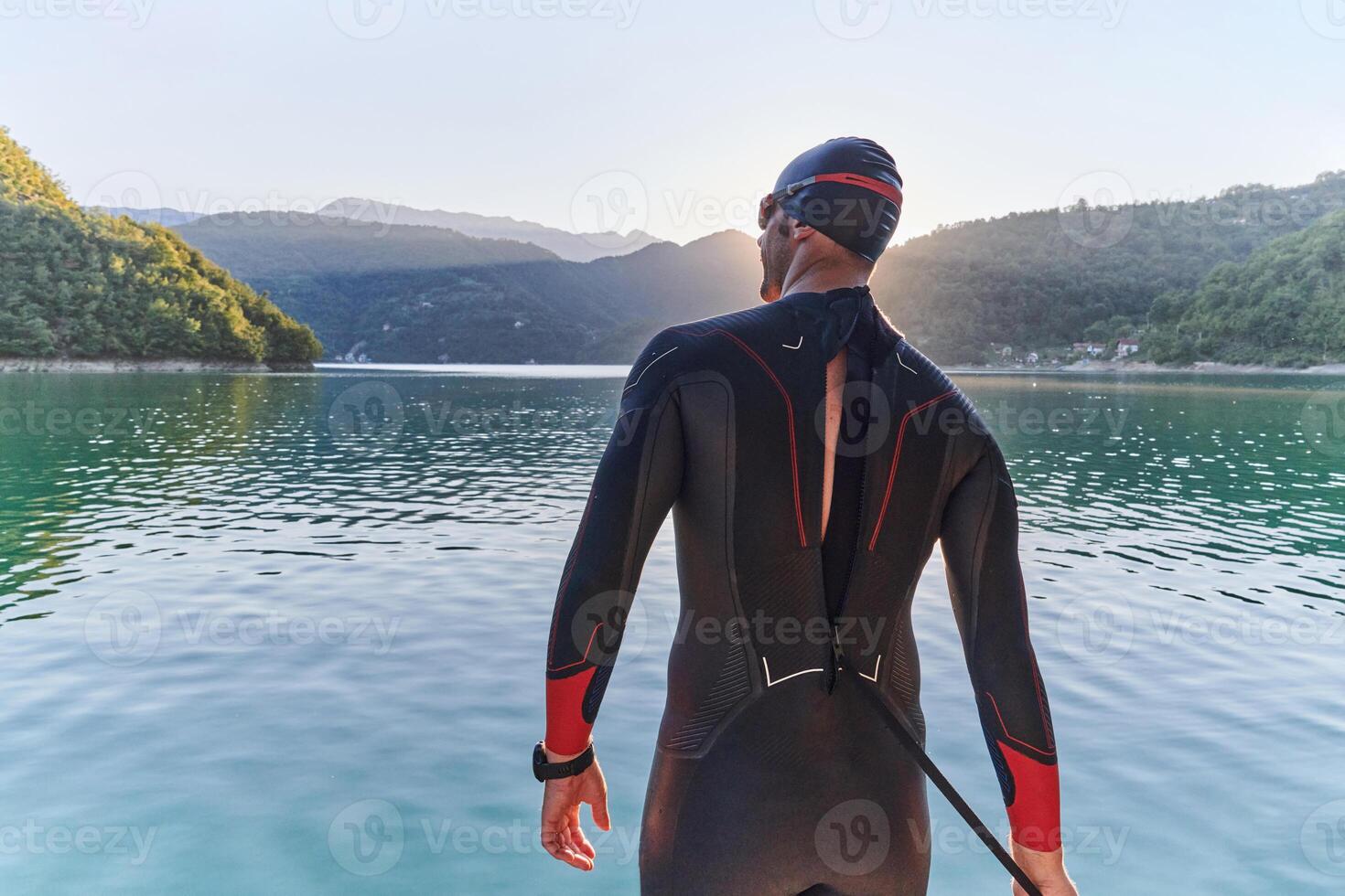 Authentic triathlon athlete getting ready for swimming training on lake photo