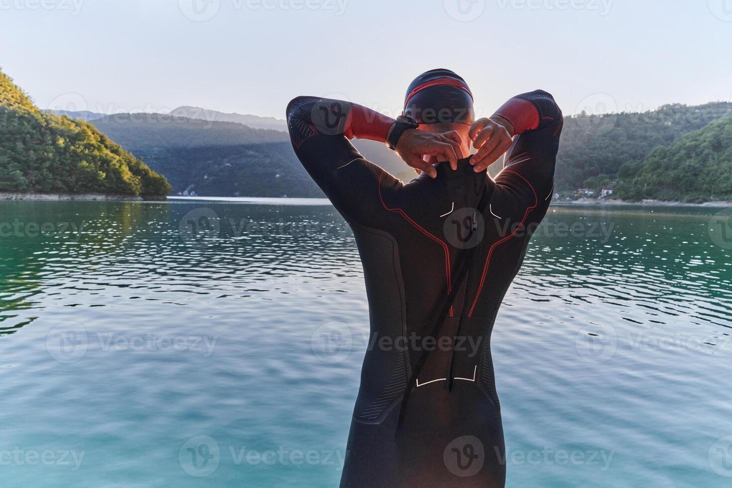 Authentic triathlon athlete getting ready for swimming training on lake photo