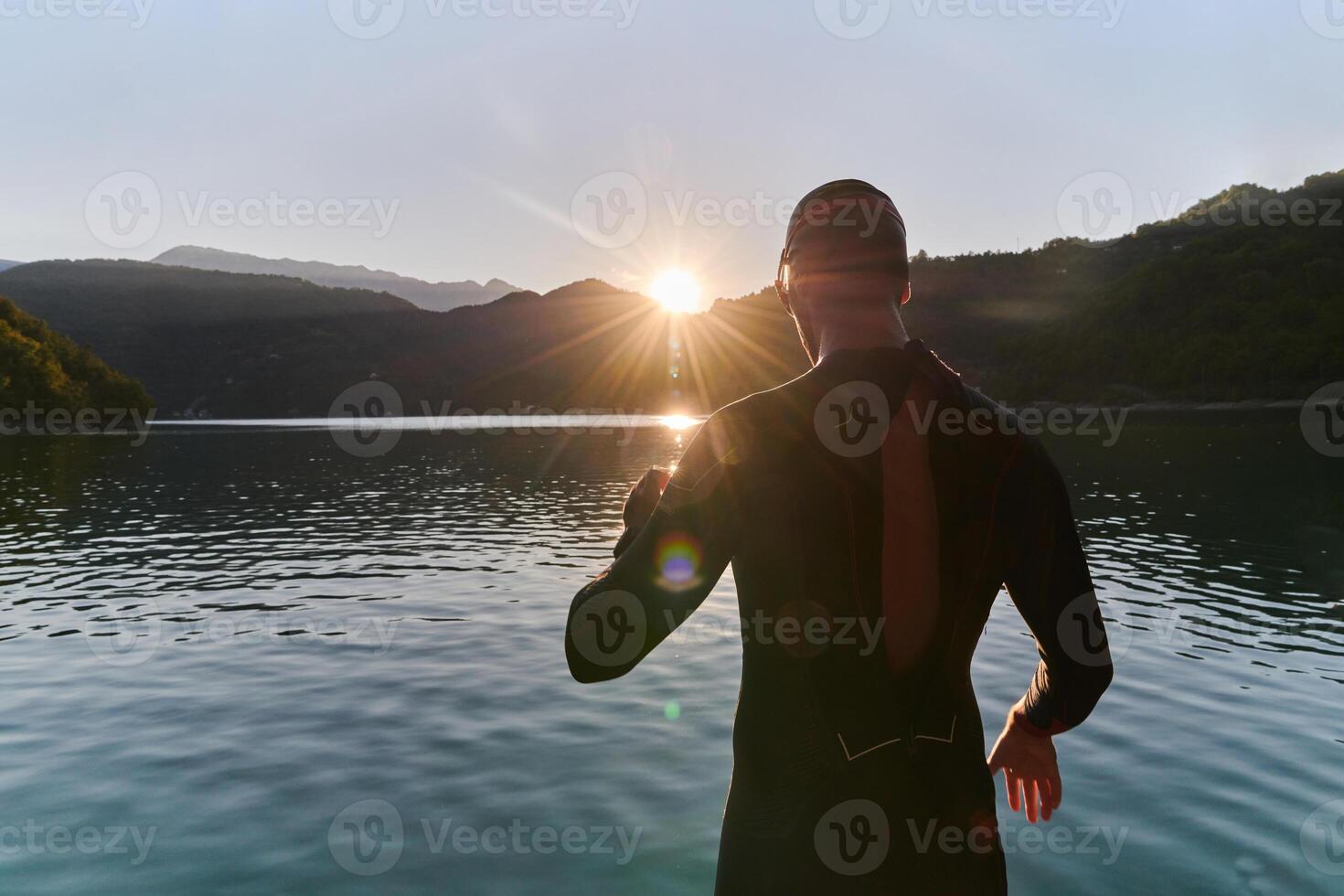 Authentic triathlon athlete getting ready for swimming training on lake photo