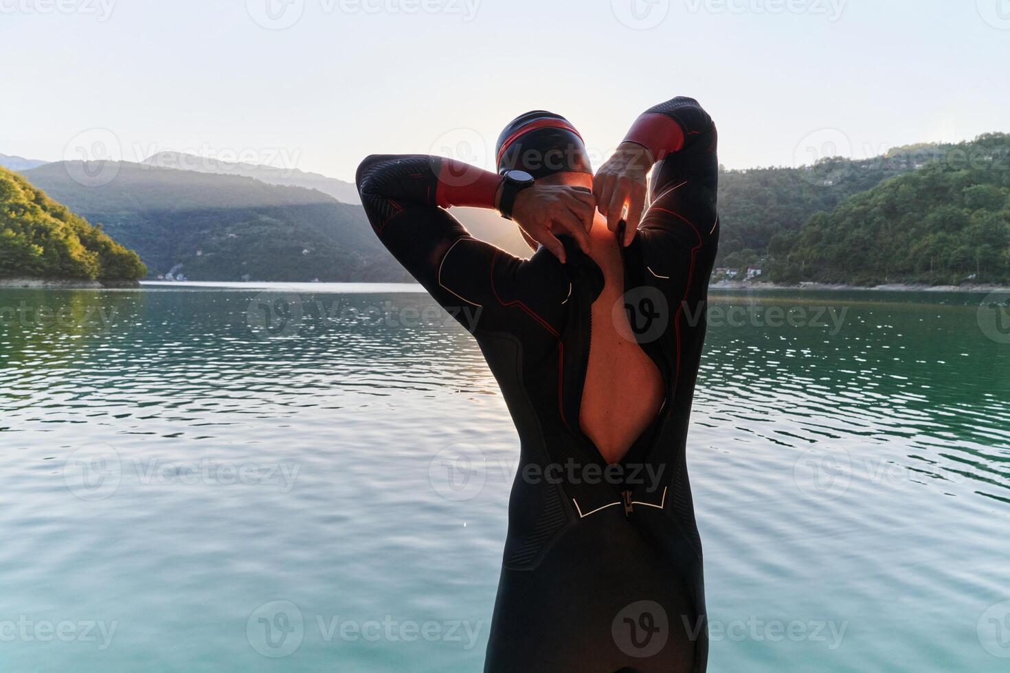 Authentic triathlon athlete getting ready for swimming training on lake photo