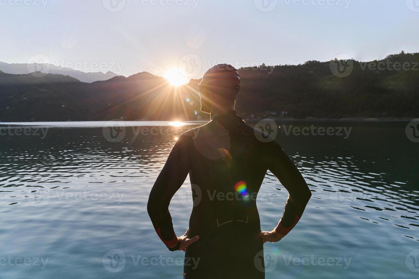 Authentic triathlon athlete getting ready for swimming training on lake photo