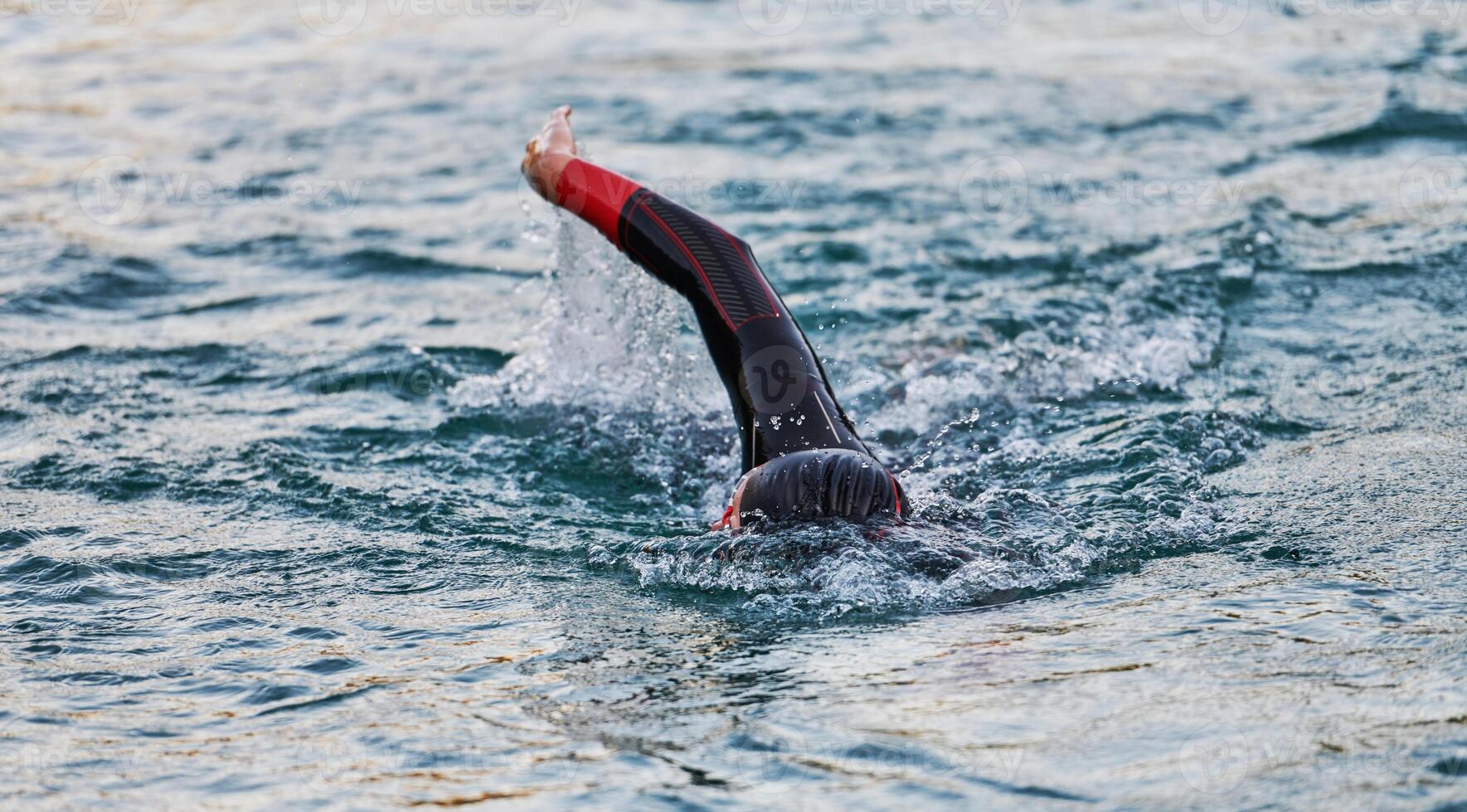 A professional triathlete trains with unwavering dedication for an upcoming competition at a lake, emanating a sense of athleticism and profound commitment to excellence. photo