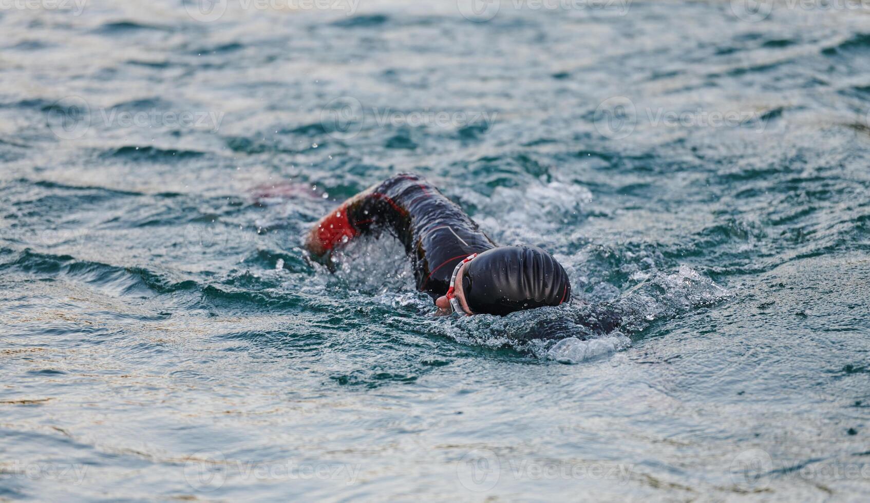 A professional triathlete trains with unwavering dedication for an upcoming competition at a lake, emanating a sense of athleticism and profound commitment to excellence. photo