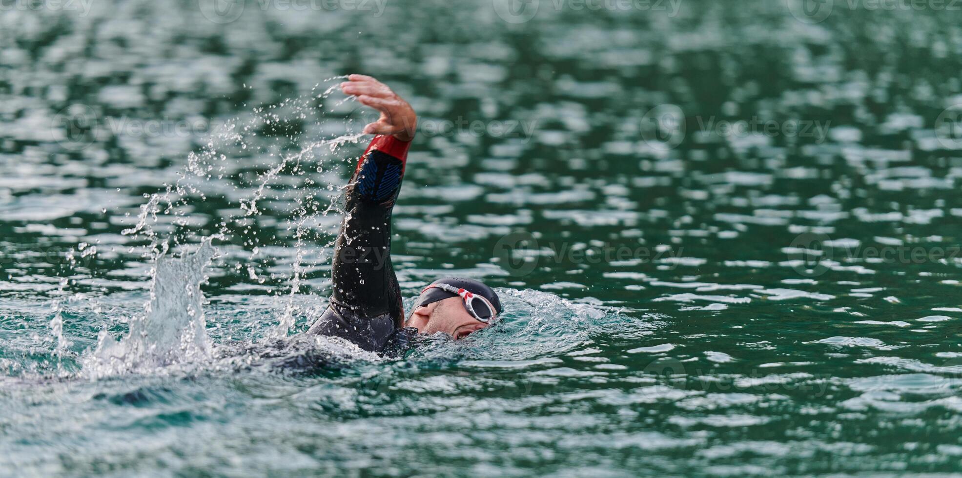 A professional triathlete trains with unwavering dedication for an upcoming competition at a lake, emanating a sense of athleticism and profound commitment to excellence. photo