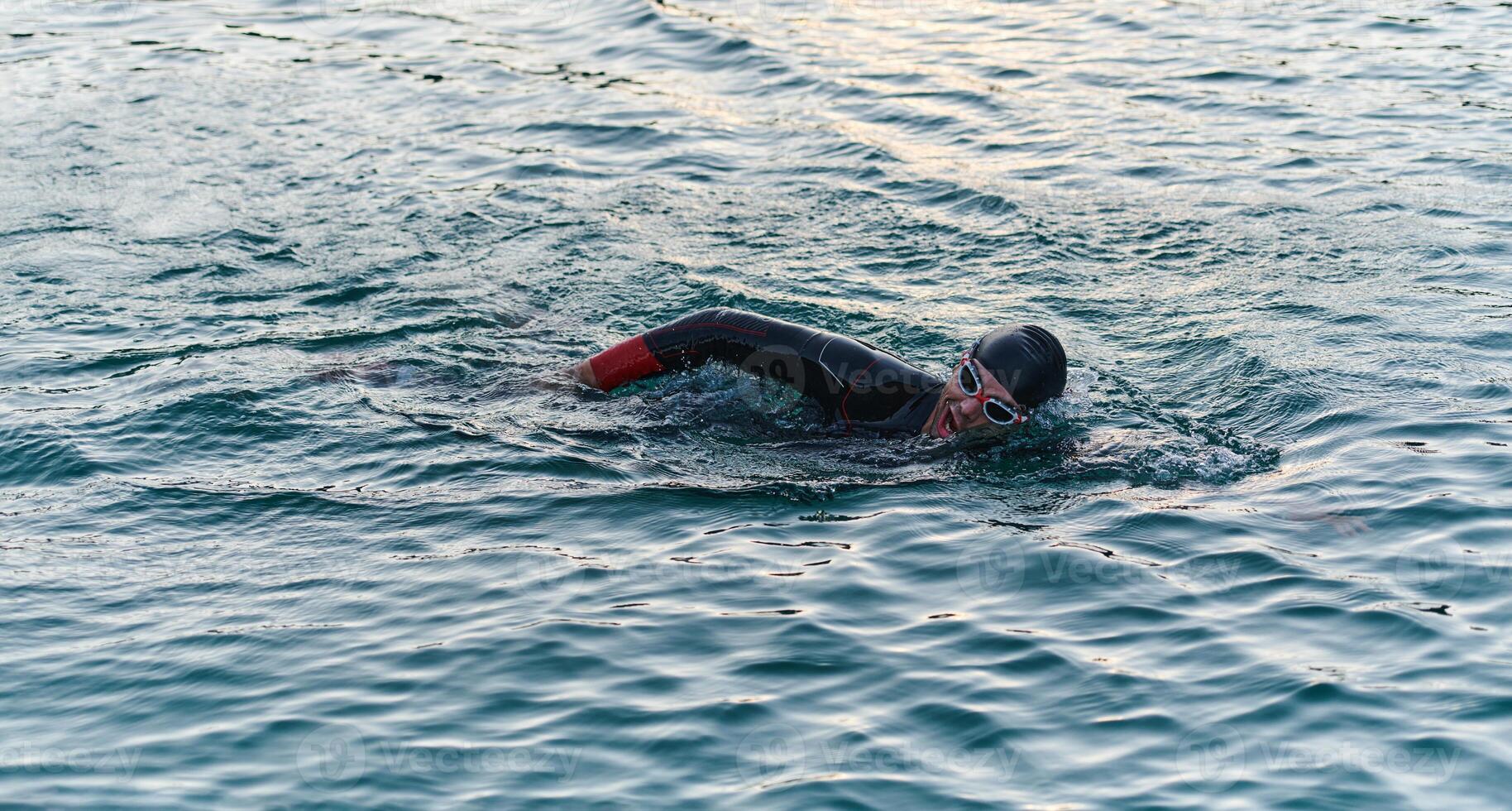 A professional triathlete trains with unwavering dedication for an upcoming competition at a lake, emanating a sense of athleticism and profound commitment to excellence. photo