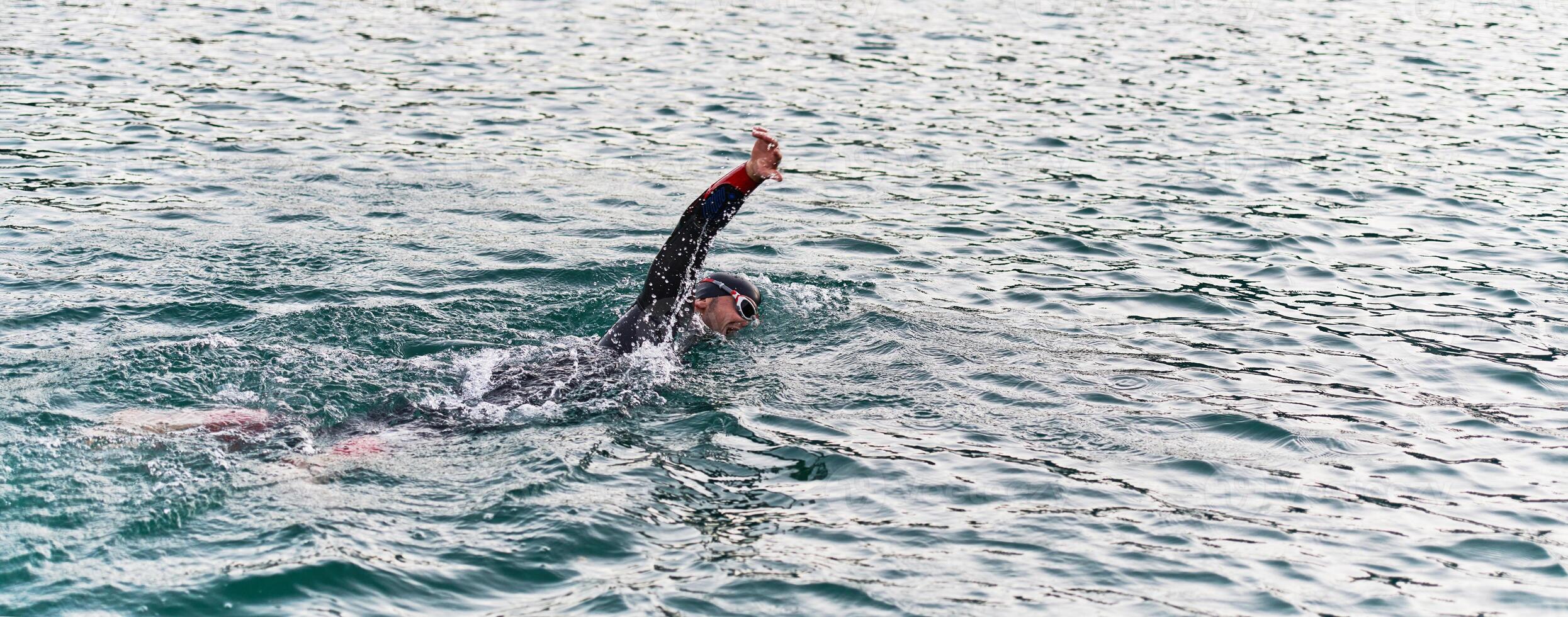 A professional triathlete trains with unwavering dedication for an upcoming competition at a lake, emanating a sense of athleticism and profound commitment to excellence. photo