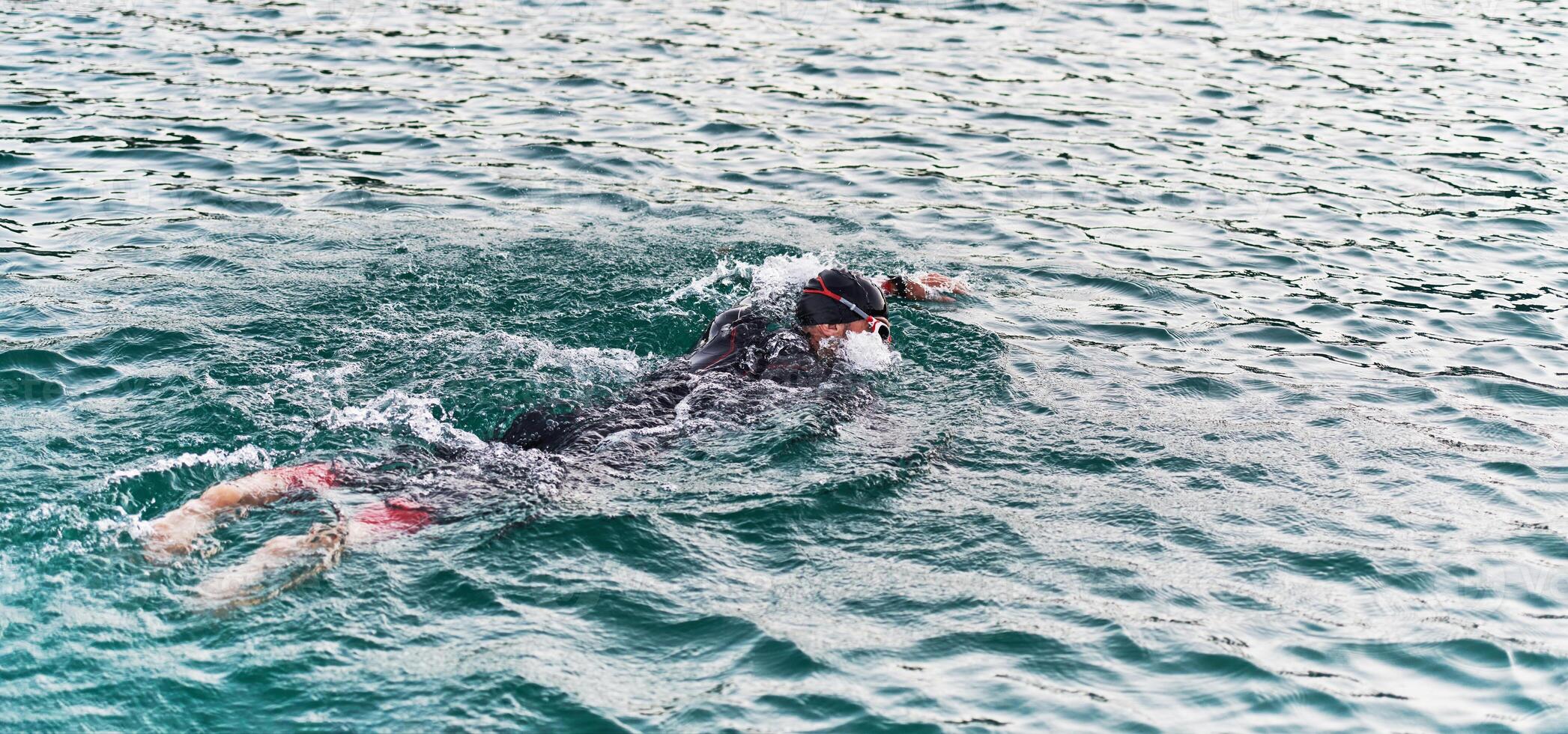 A professional triathlete trains with unwavering dedication for an upcoming competition at a lake, emanating a sense of athleticism and profound commitment to excellence. photo