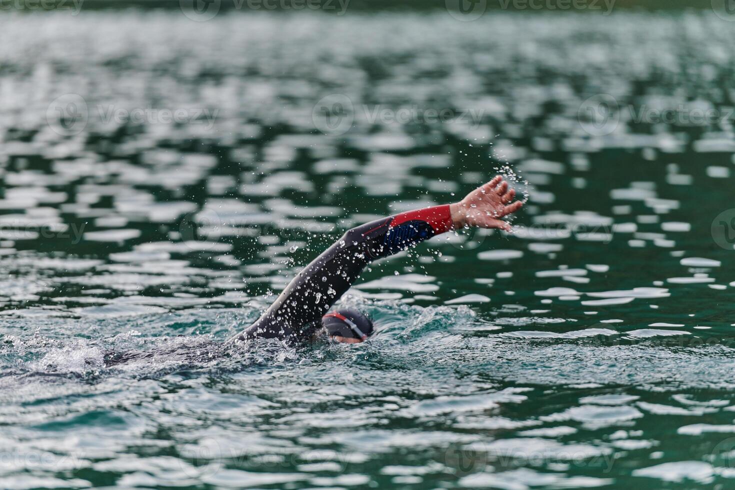 A professional triathlete trains with unwavering dedication for an upcoming competition at a lake, emanating a sense of athleticism and profound commitment to excellence. photo
