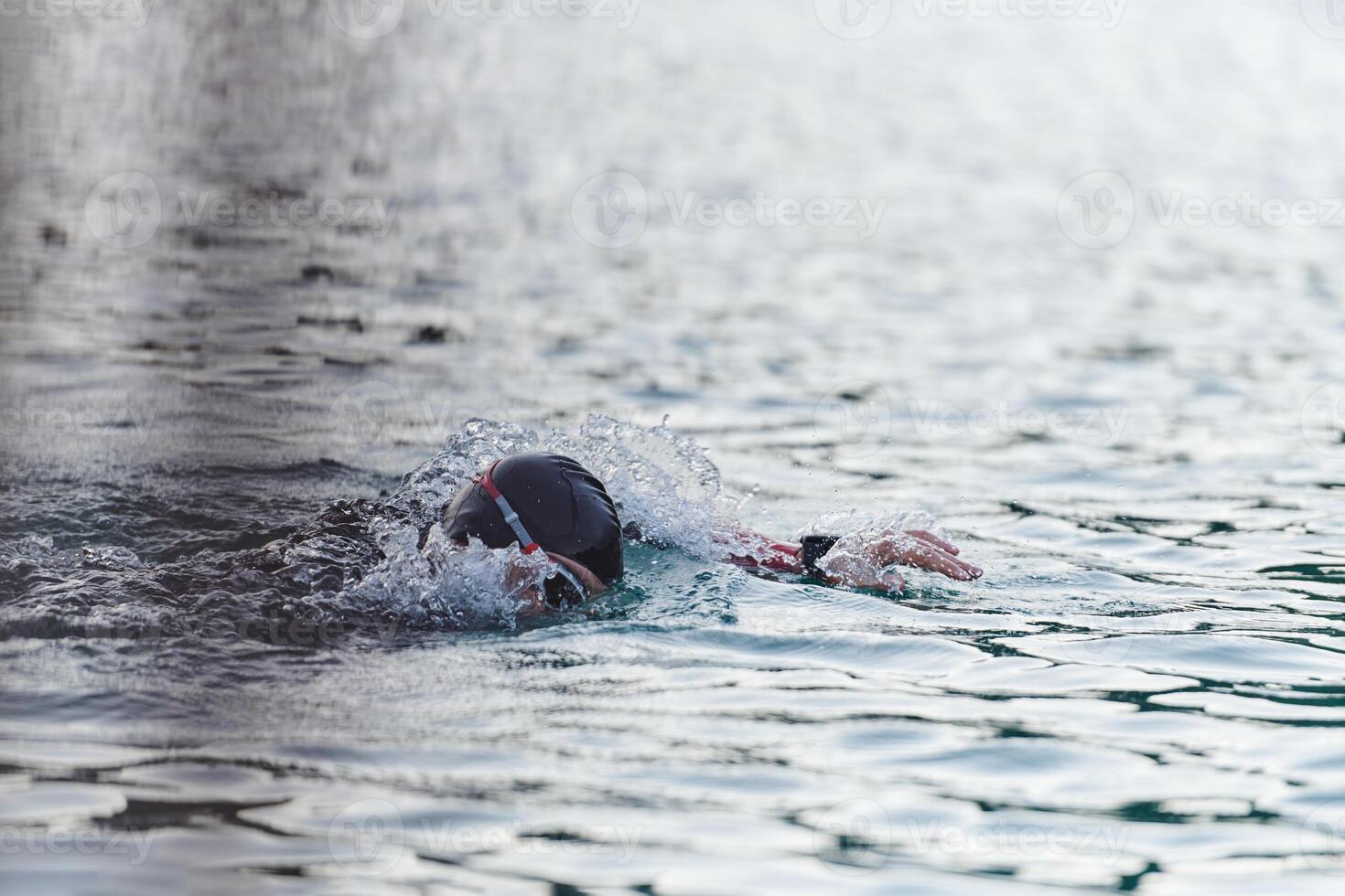 A professional triathlete trains with unwavering dedication for an upcoming competition at a lake, emanating a sense of athleticism and profound commitment to excellence. photo
