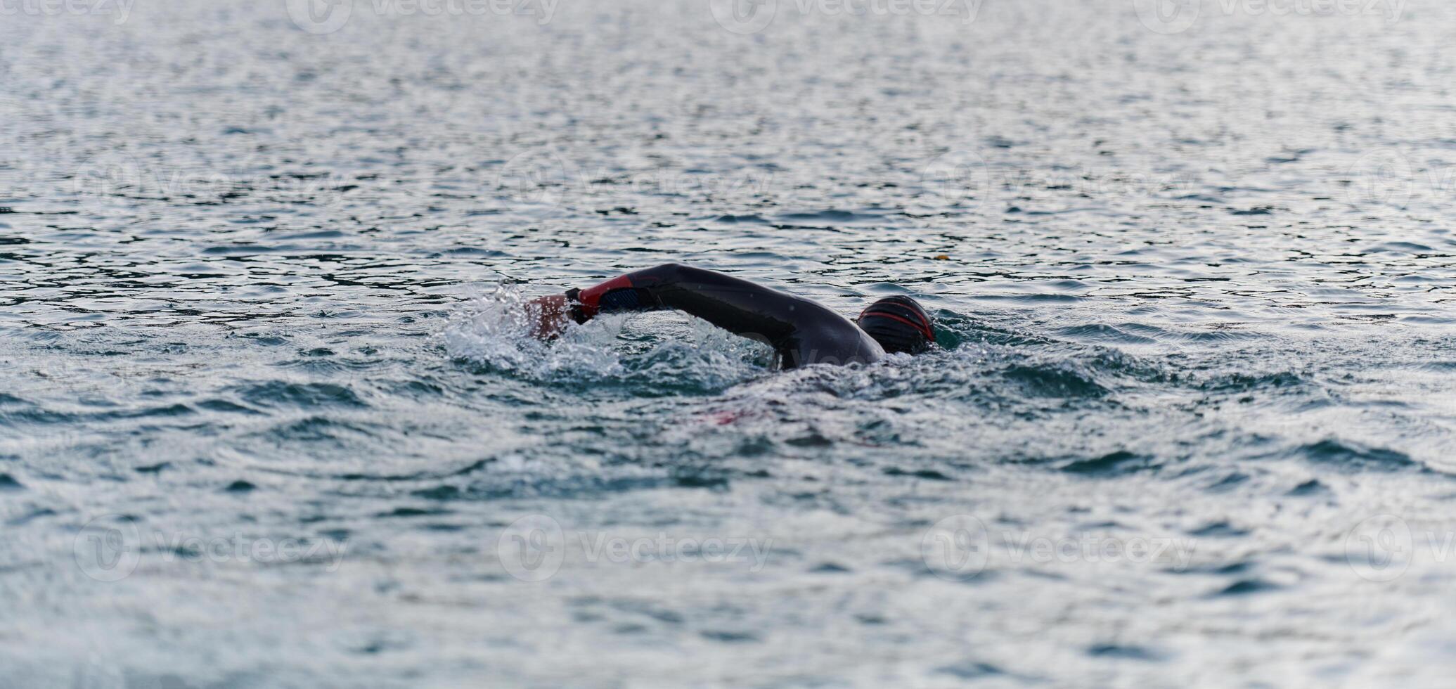 A professional triathlete trains with unwavering dedication for an upcoming competition at a lake, emanating a sense of athleticism and profound commitment to excellence. photo