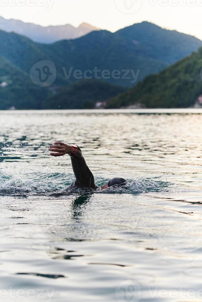 A professional triathlete trains with unwavering dedication for an upcoming competition at a lake, emanating a sense of athleticism and profound commitment to excellence. photo