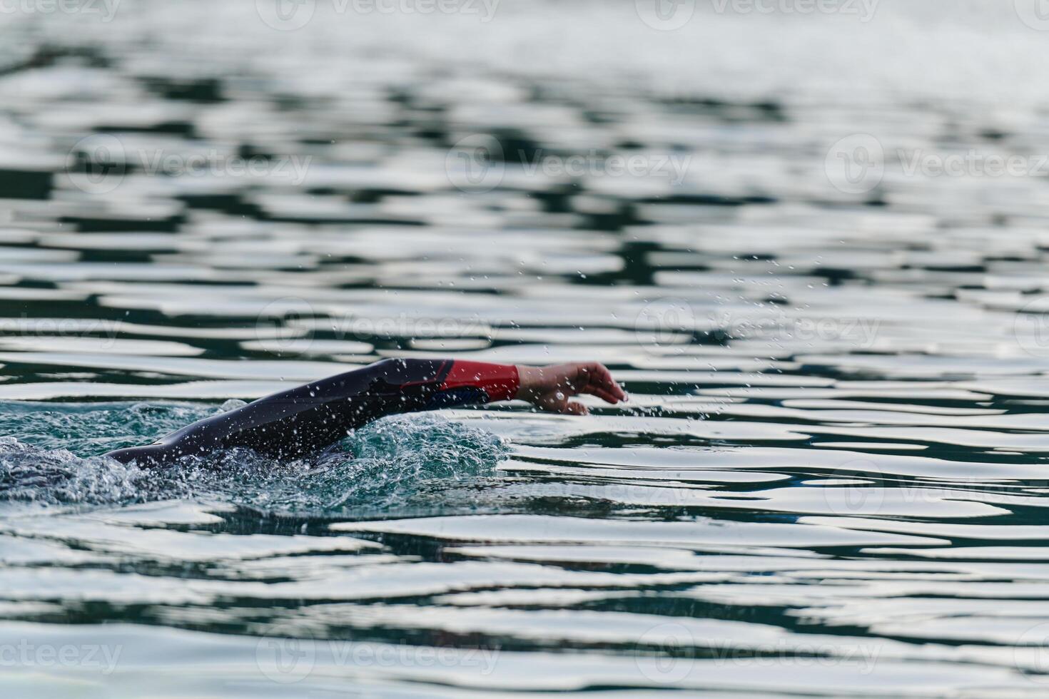 A professional triathlete trains with unwavering dedication for an upcoming competition at a lake, emanating a sense of athleticism and profound commitment to excellence. photo