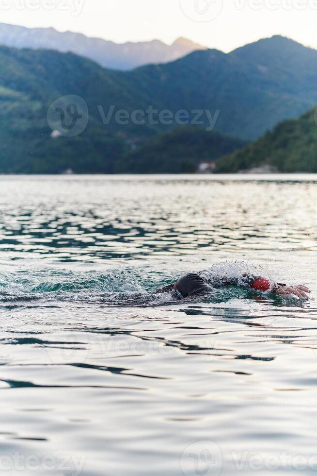 A professional triathlete trains with unwavering dedication for an upcoming competition at a lake, emanating a sense of athleticism and profound commitment to excellence. photo