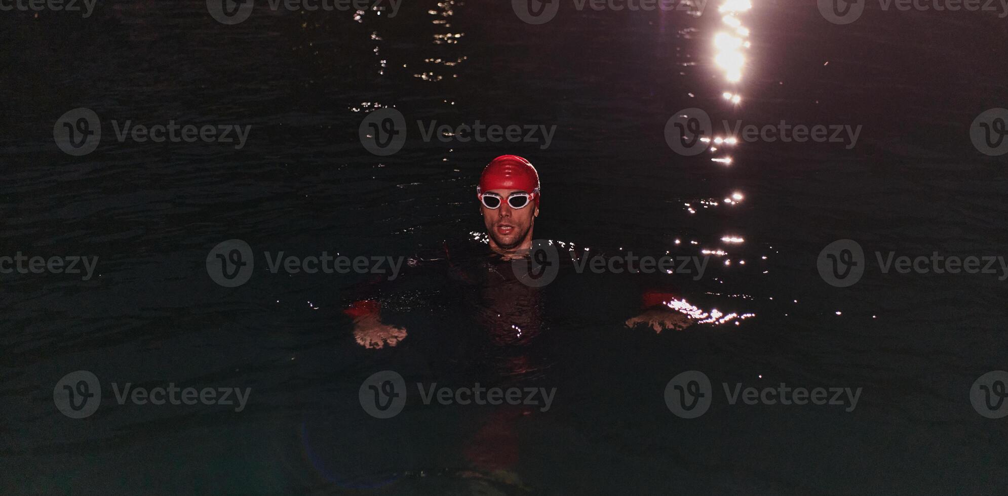 A determined professional triathlete undergoes rigorous night time training in cold waters, showcasing dedication and resilience in preparation for an upcoming triathlon swim competition photo