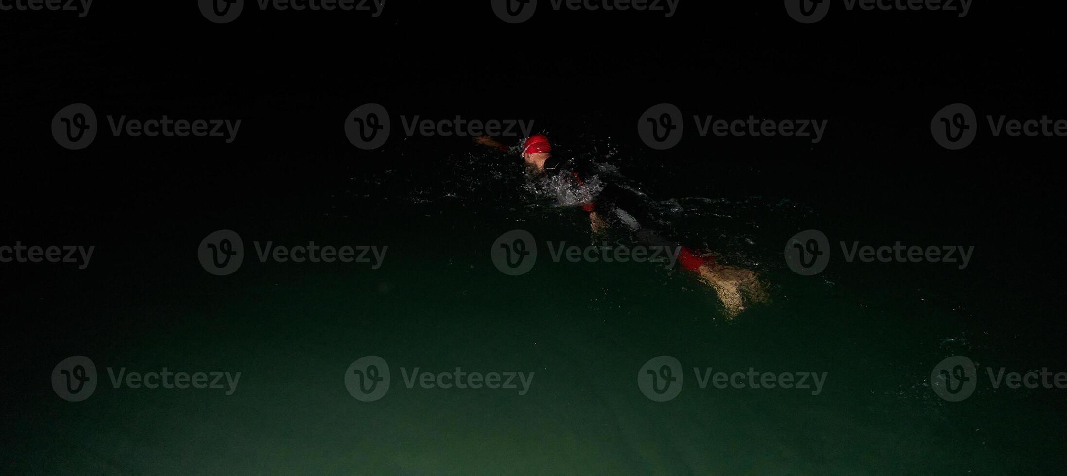 A determined professional triathlete undergoes rigorous night time training in cold waters, showcasing dedication and resilience in preparation for an upcoming triathlon swim competition photo