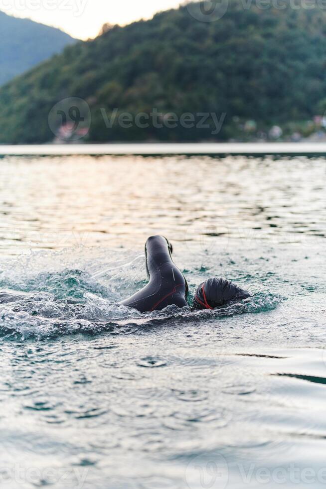 A professional triathlete trains with unwavering dedication for an upcoming competition at a lake, emanating a sense of athleticism and profound commitment to excellence. photo