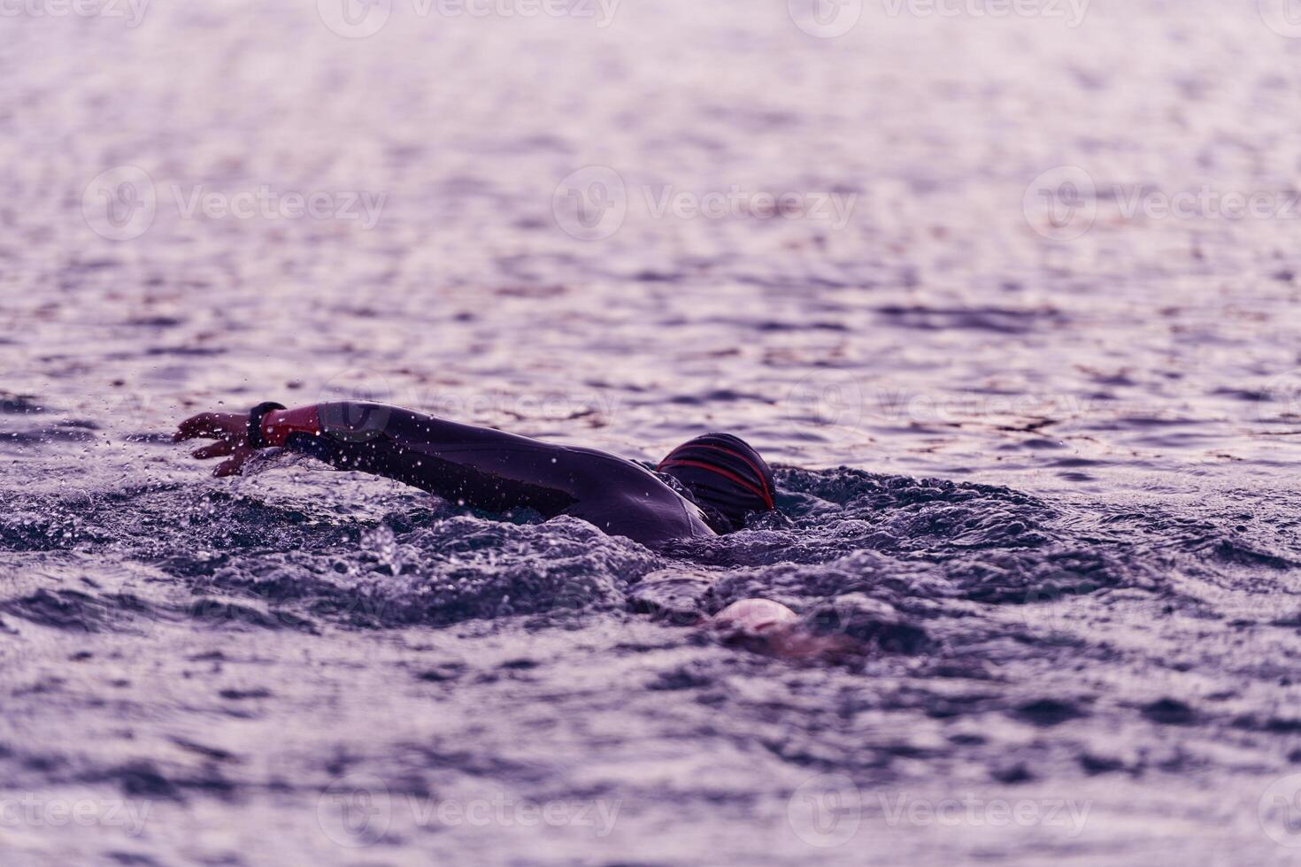 A professional triathlete trains with unwavering dedication for an upcoming competition at a lake, emanating a sense of athleticism and profound commitment to excellence. photo
