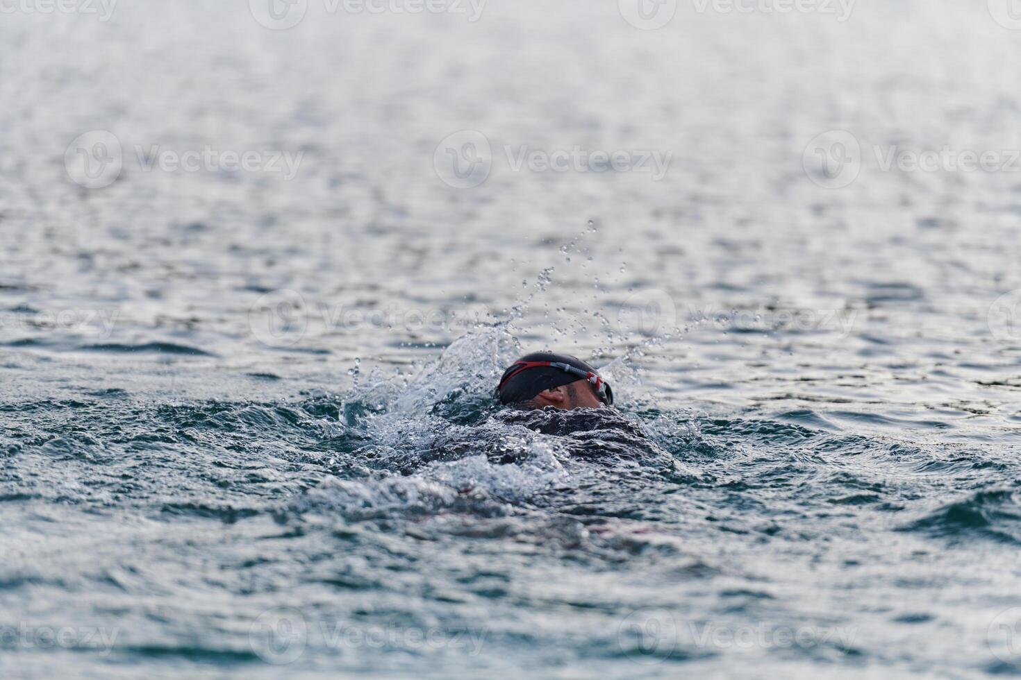 A professional triathlete trains with unwavering dedication for an upcoming competition at a lake, emanating a sense of athleticism and profound commitment to excellence. photo