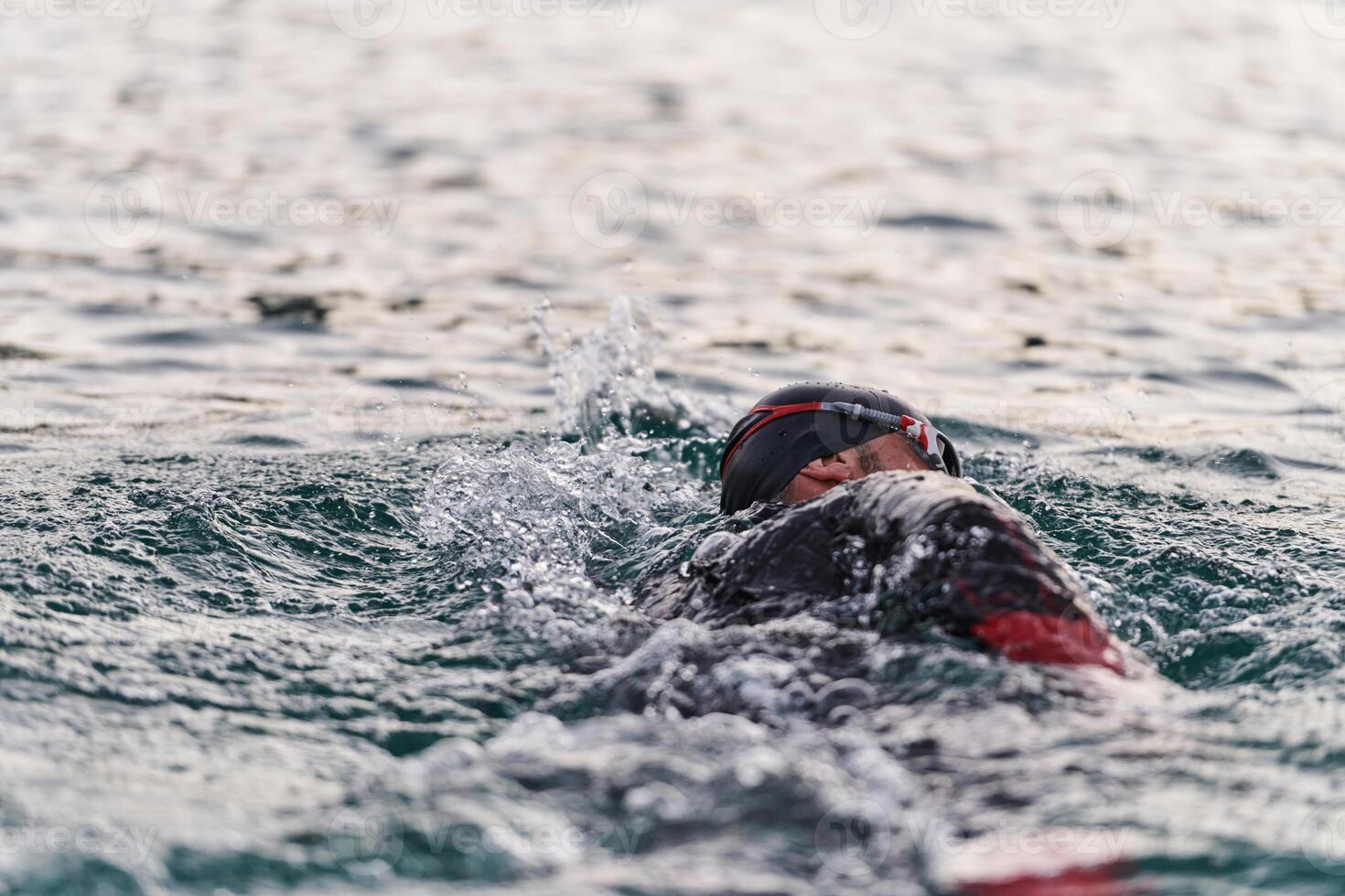 A professional triathlete trains with unwavering dedication for an upcoming competition at a lake, emanating a sense of athleticism and profound commitment to excellence. photo