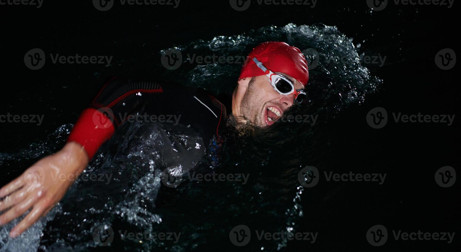 A determined professional triathlete undergoes rigorous night time training in cold waters, showcasing dedication and resilience in preparation for an upcoming triathlon swim competition photo