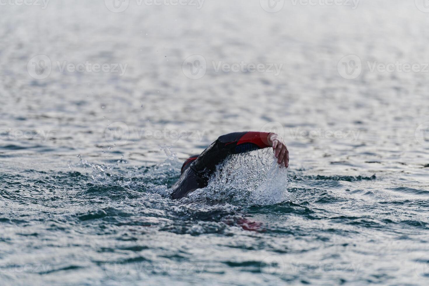 A professional triathlete trains with unwavering dedication for an upcoming competition at a lake, emanating a sense of athleticism and profound commitment to excellence. photo