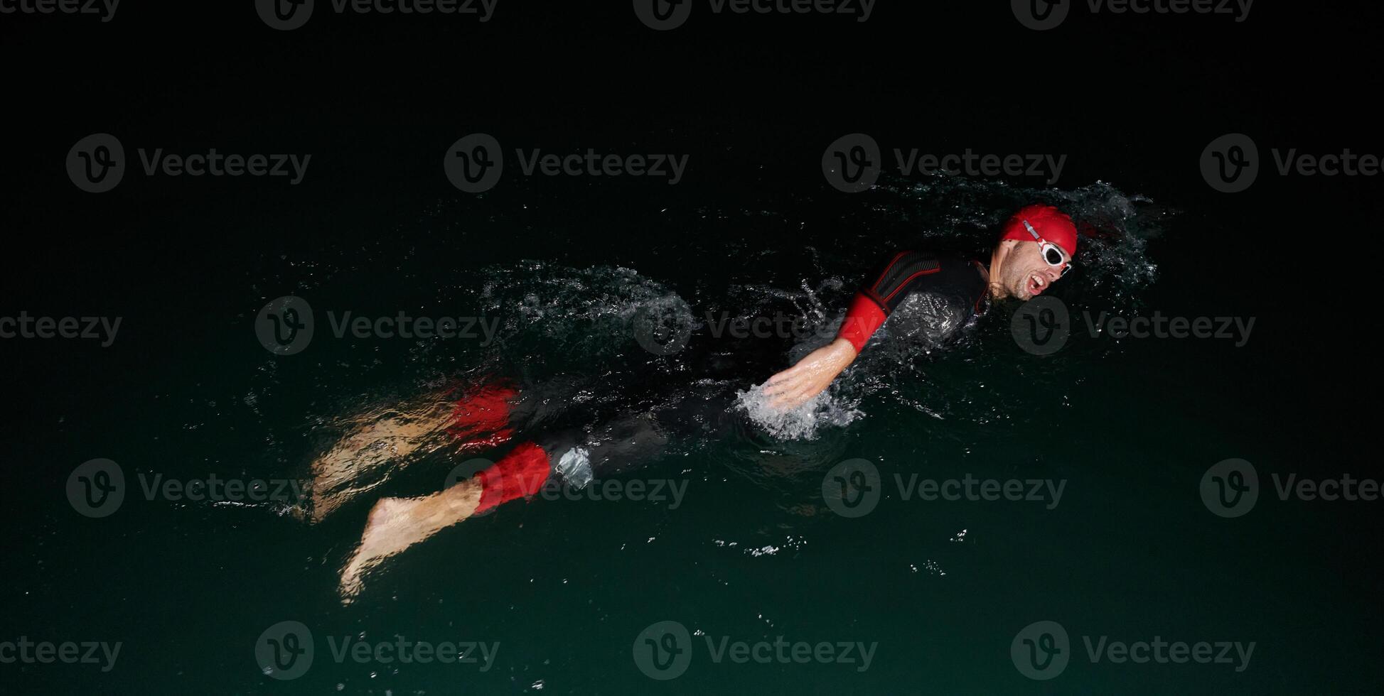 A determined professional triathlete undergoes rigorous night time training in cold waters, showcasing dedication and resilience in preparation for an upcoming triathlon swim competition photo