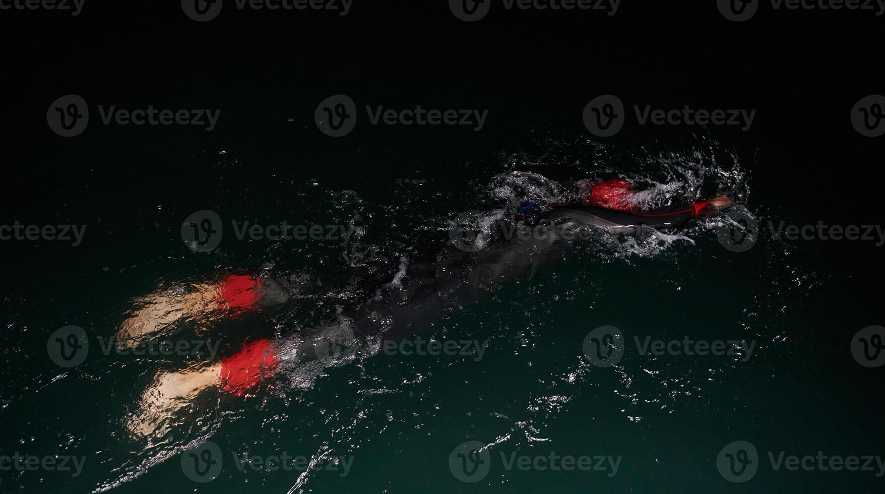 A determined professional triathlete undergoes rigorous night time training in cold waters, showcasing dedication and resilience in preparation for an upcoming triathlon swim competition photo