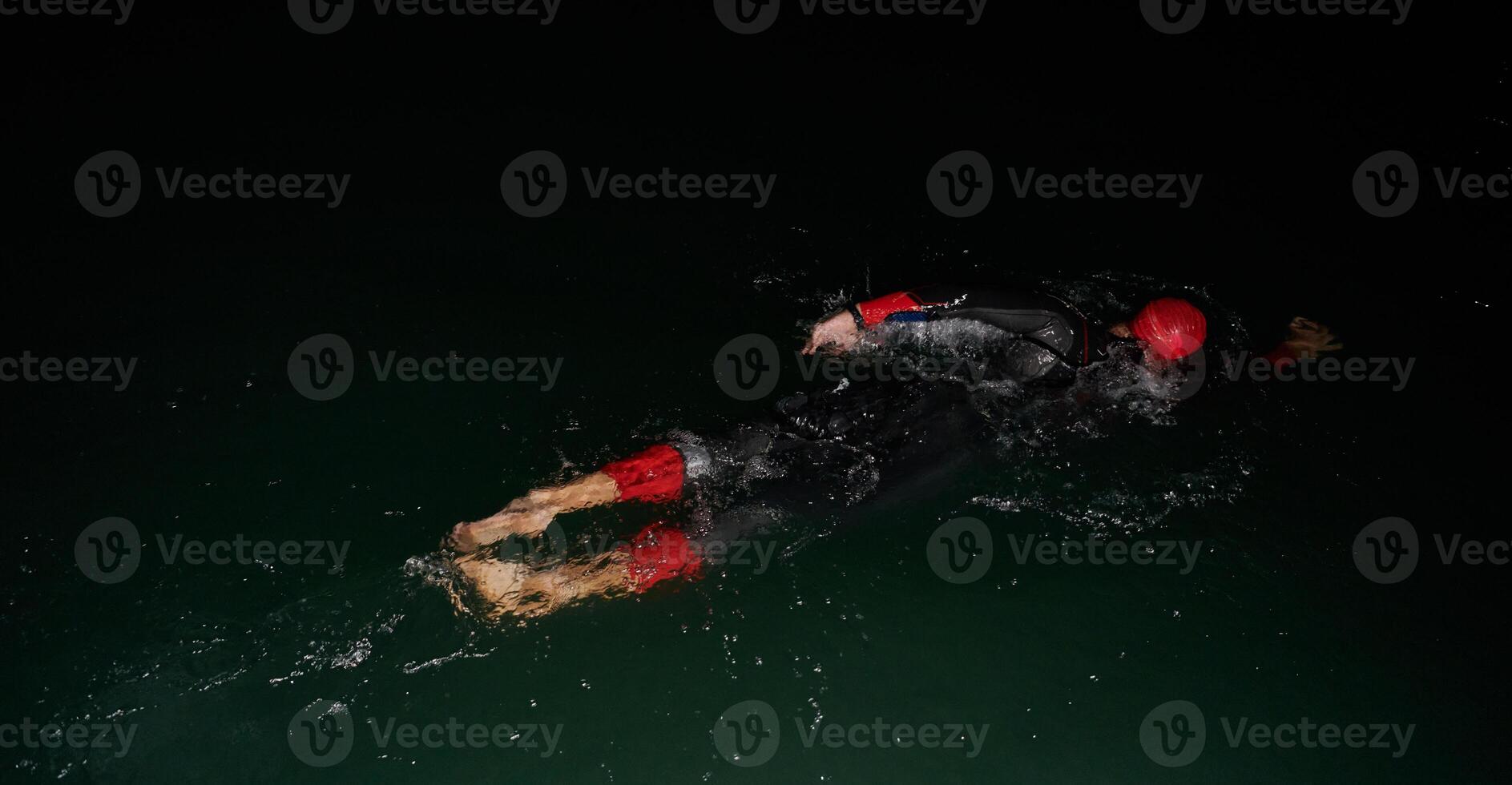 A determined professional triathlete undergoes rigorous night time training in cold waters, showcasing dedication and resilience in preparation for an upcoming triathlon swim competition photo