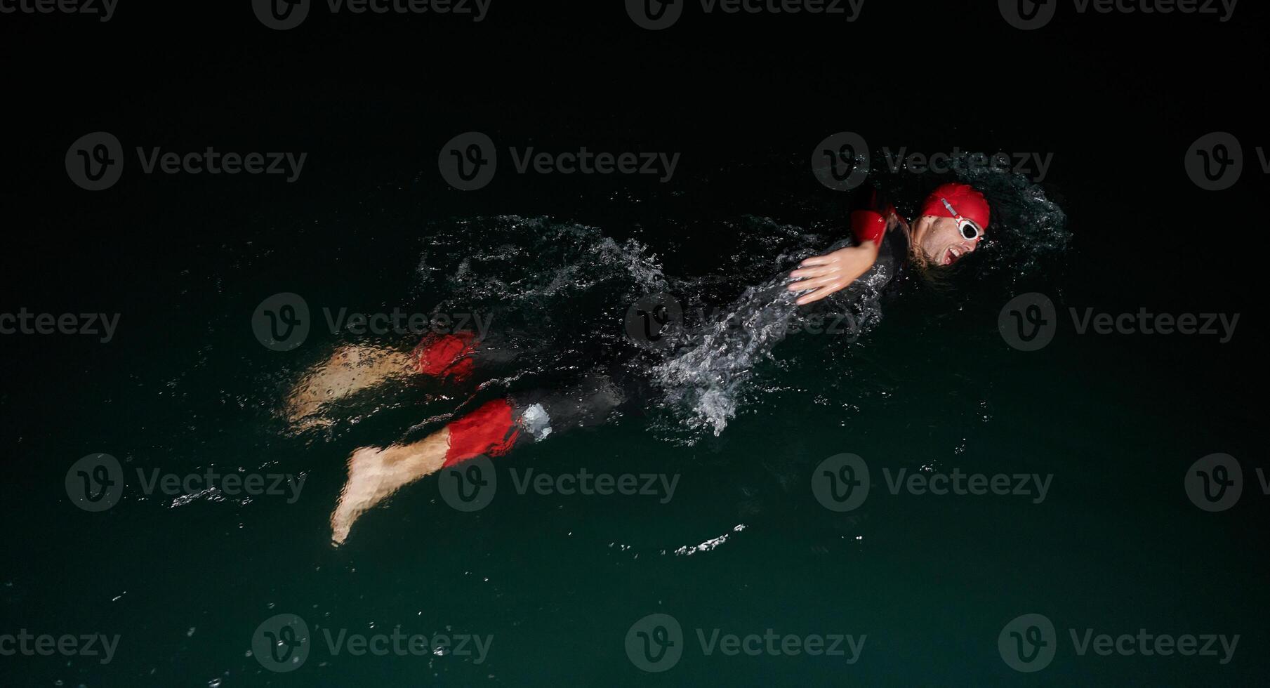 A determined professional triathlete undergoes rigorous night time training in cold waters, showcasing dedication and resilience in preparation for an upcoming triathlon swim competition photo