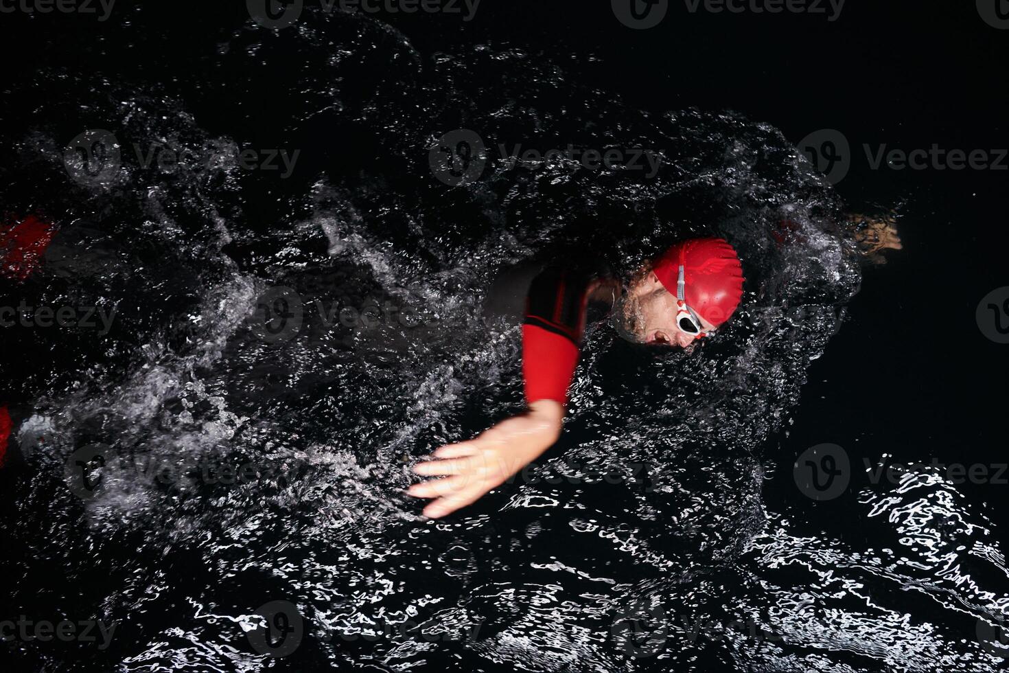 A determined professional triathlete undergoes rigorous night time training in cold waters, showcasing dedication and resilience in preparation for an upcoming triathlon swim competition photo