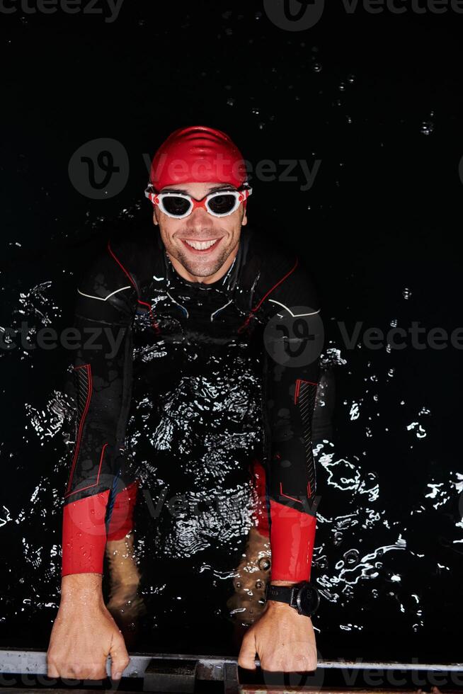 A determined professional triathlete undergoes rigorous night time training in cold waters, showcasing dedication and resilience in preparation for an upcoming triathlon swim competition photo