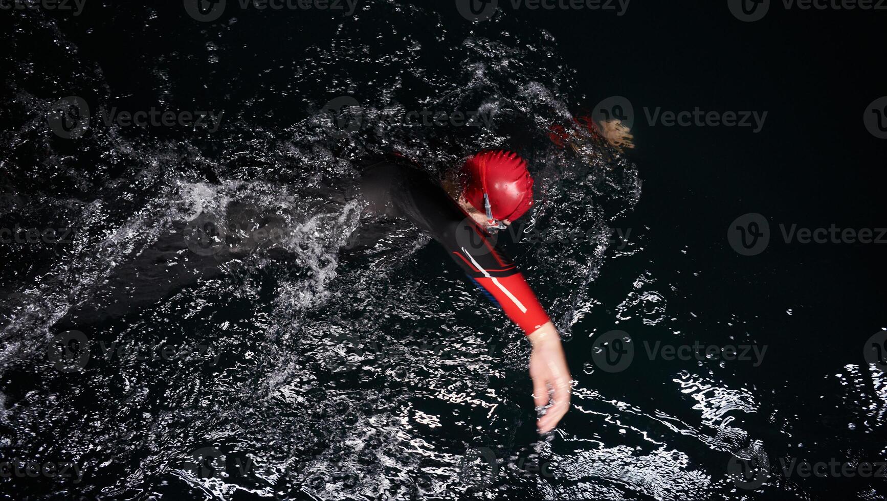 A determined professional triathlete undergoes rigorous night time training in cold waters, showcasing dedication and resilience in preparation for an upcoming triathlon swim competition photo