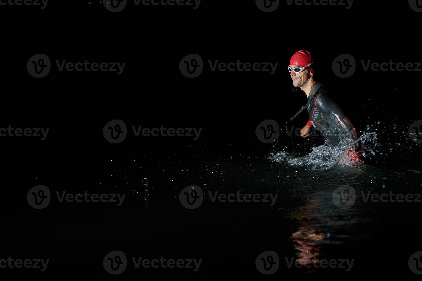 A determined professional triathlete undergoes rigorous night time training in cold waters, showcasing dedication and resilience in preparation for an upcoming triathlon swim competition photo