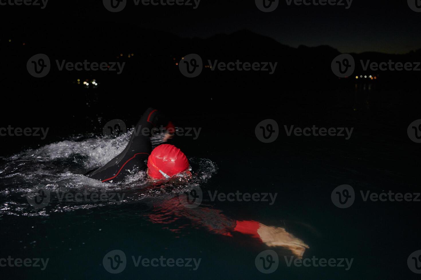 A determined professional triathlete undergoes rigorous night time training in cold waters, showcasing dedication and resilience in preparation for an upcoming triathlon swim competition photo