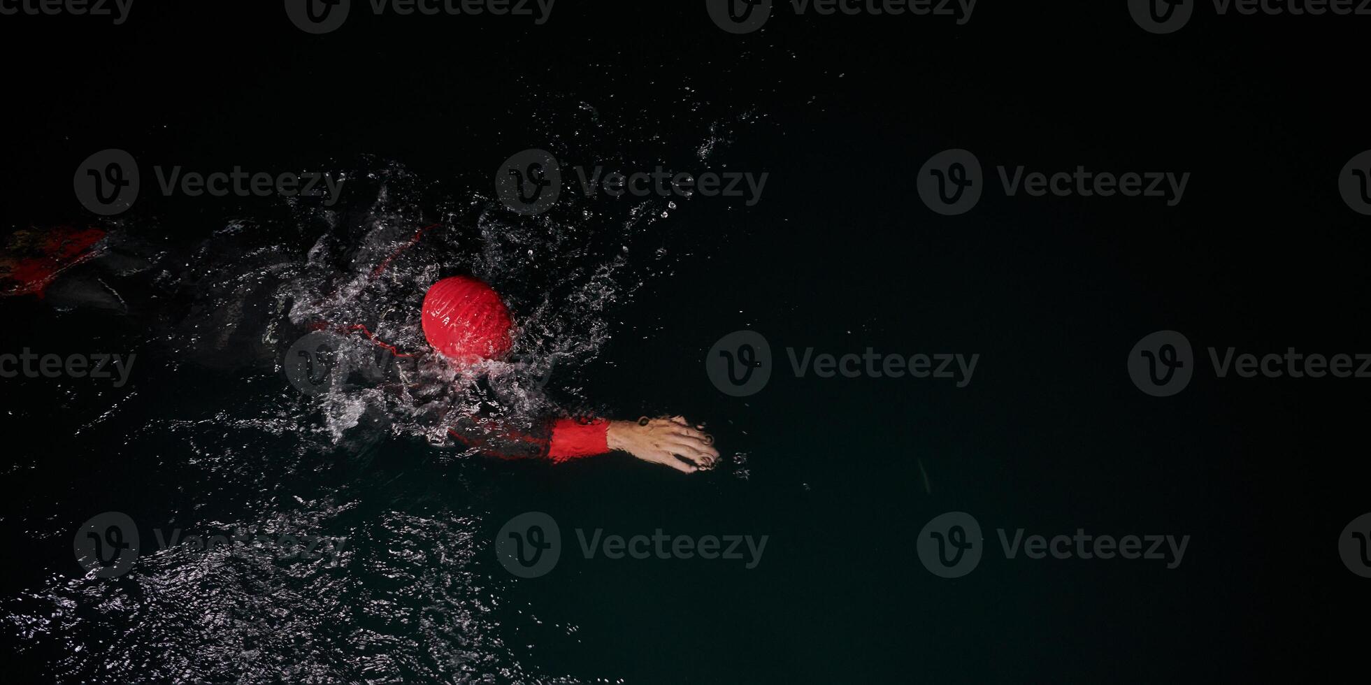 A determined professional triathlete undergoes rigorous night time training in cold waters, showcasing dedication and resilience in preparation for an upcoming triathlon swim competition photo