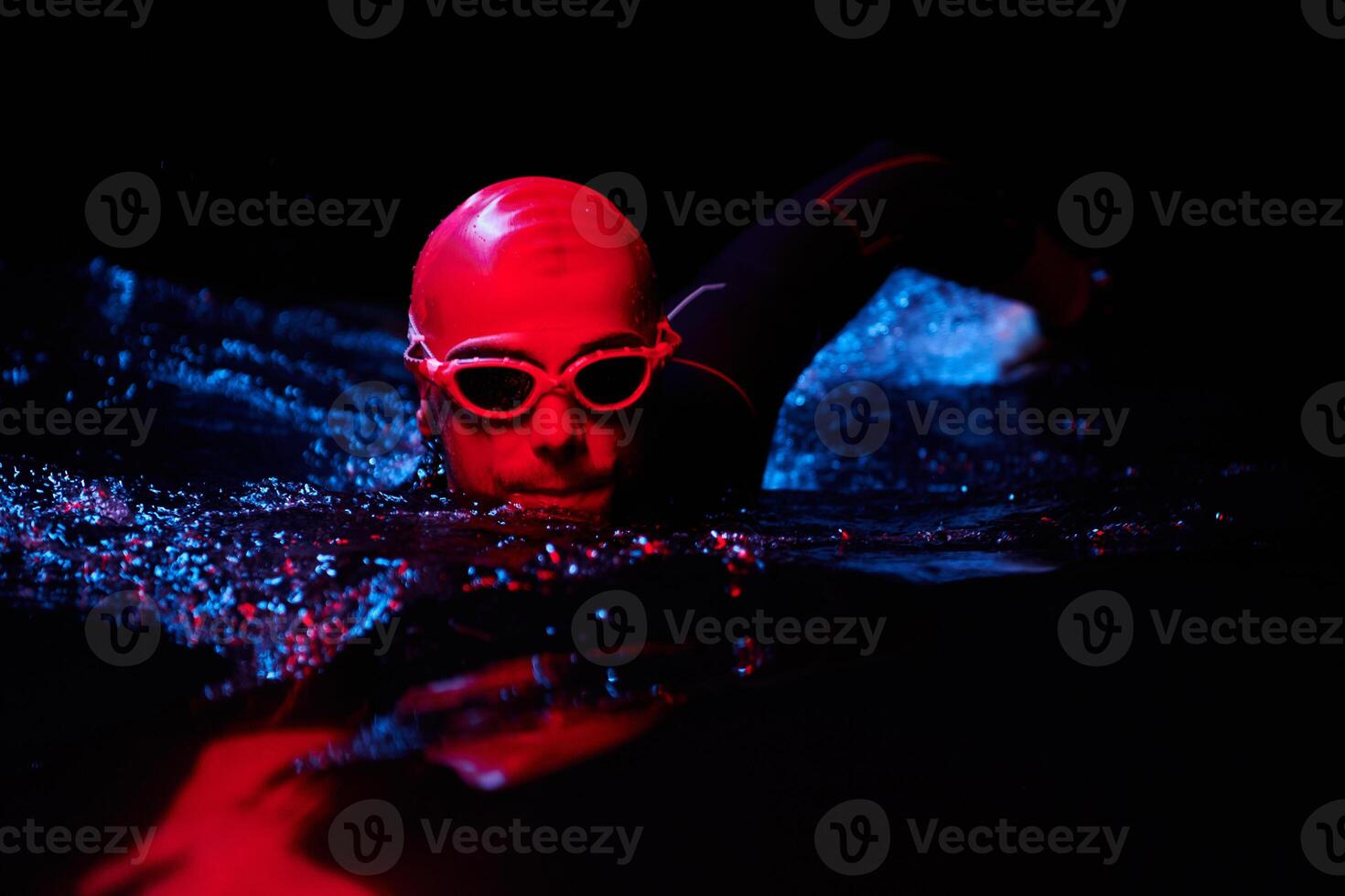 authentic triathlete swimmer having a break during hard training on night neon gel light photo