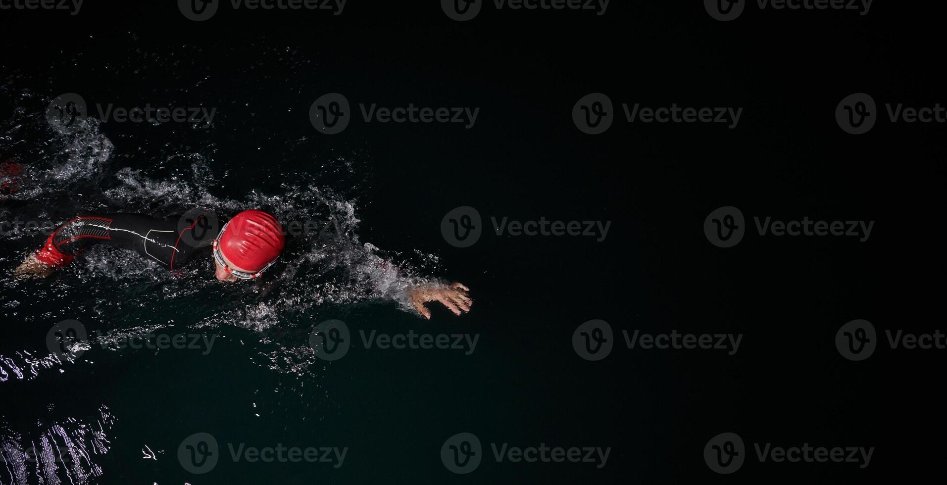 A determined professional triathlete undergoes rigorous night time training in cold waters, showcasing dedication and resilience in preparation for an upcoming triathlon swim competition photo