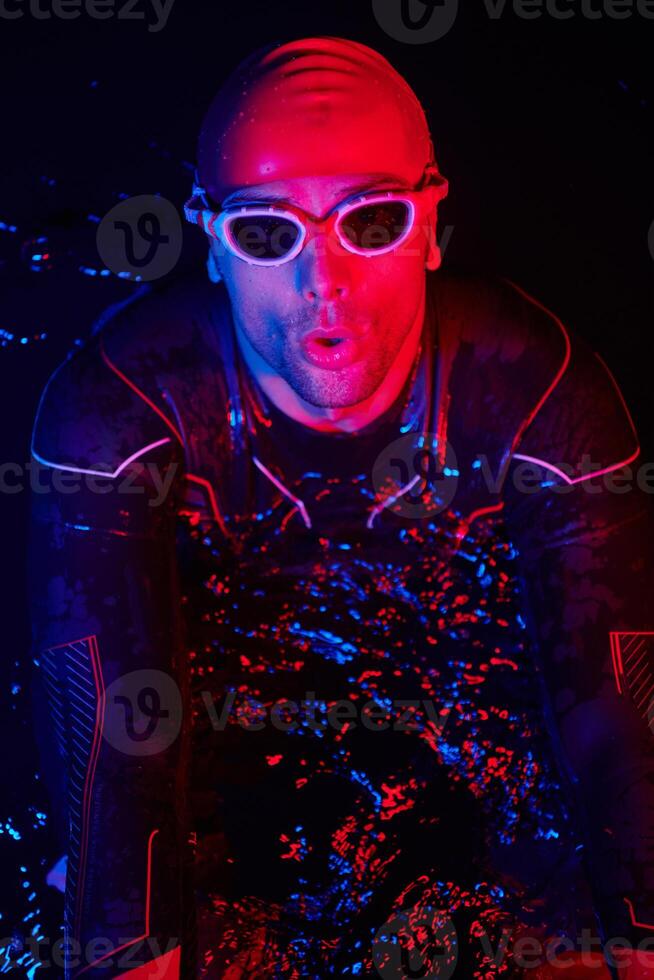 authentic triathlete swimmer having a break during hard training on night neon gel light photo