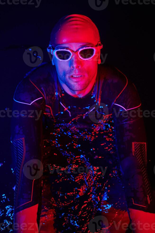 authentic triathlete swimmer having a break during hard training on night neon gel light photo
